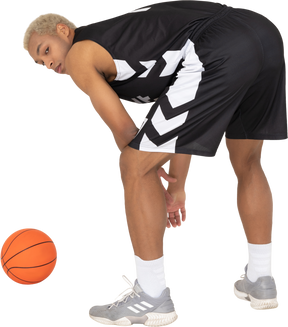 Dreiviertel-rückansicht eines jungen männlichen basketballspielers, der am ball steht