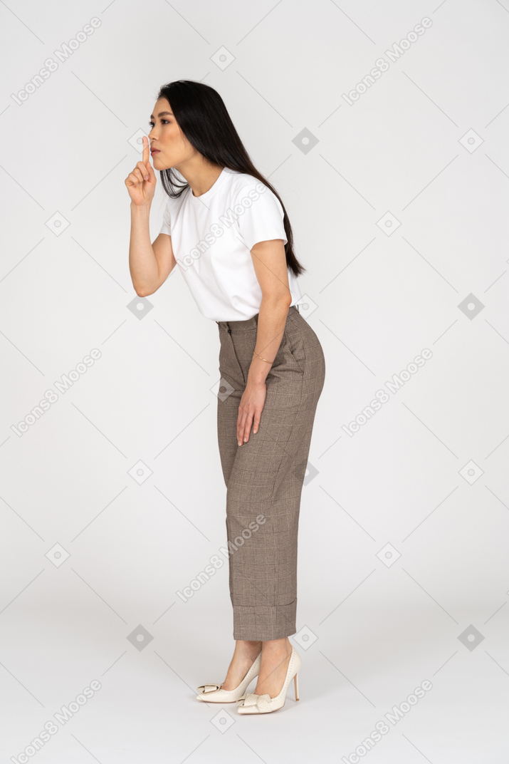 Vue de trois quarts d'une jeune femme en culotte et t-shirt montrant un geste de silence