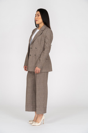 Three-quarter view of a young lady in brown business suit standing with her eyes closed