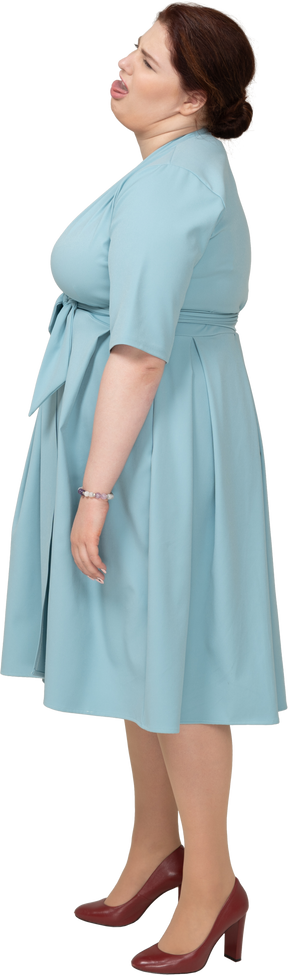 Vue latérale d'une femme en robe bleue faisant des grimaces