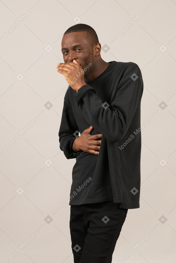 Mischievous man with hand on stomach covering his mouth