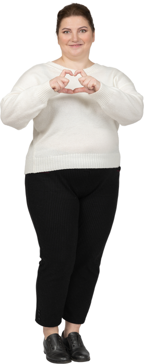 Happy plump woman in casual clothes showing heart figure