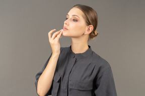 Three-quarter view of a young woman in a jumpsuit removing make-up