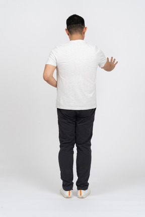 Вид сзади человека в повседневной одежде, показывающего жест стоп