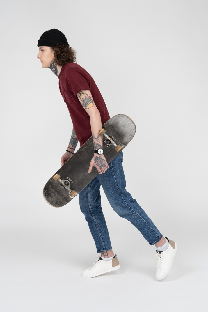 A teenager walking with his skateboard