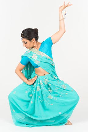 Giovane donna indiana in sari blu in piedi in posizione di danza