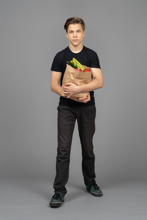 Jeune, debout, contre, appareil photo, papier, sac, rempli, fruit, legumes