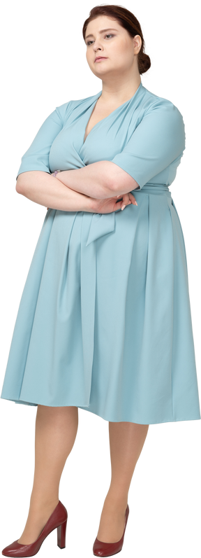 Вид спереди женщины в синем платье позирует со скрещенными руками