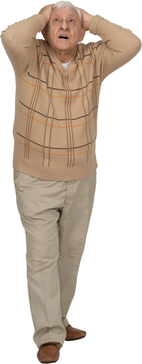 Vista frontal de un anciano impresionado con ropa informal de pie con las manos detrás de la cabeza
