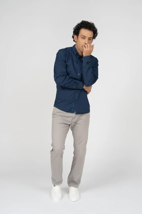 Front view of a man in casual clothes biting his fingers