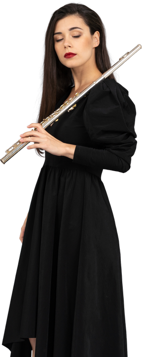 Vista de tres cuartos de una joven soñolienta en vestido negro sosteniendo flauta