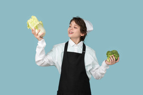 Kid boy chef holding chinese cabbage and broccoli