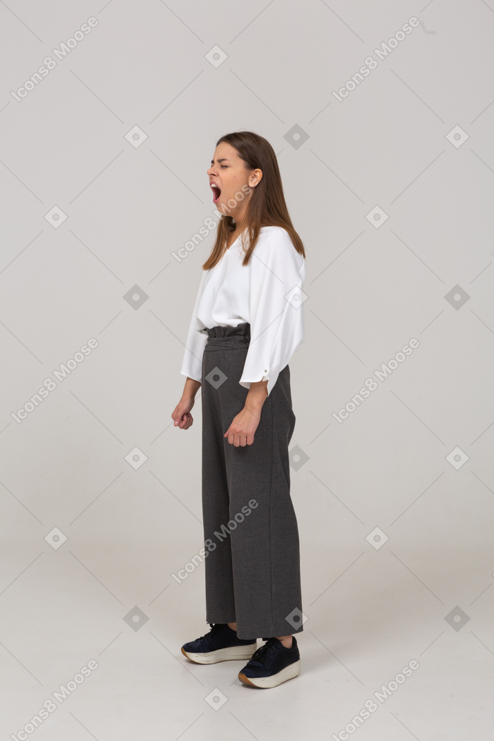 Vista de tres cuartos de una señorita bostezo en ropa de oficina