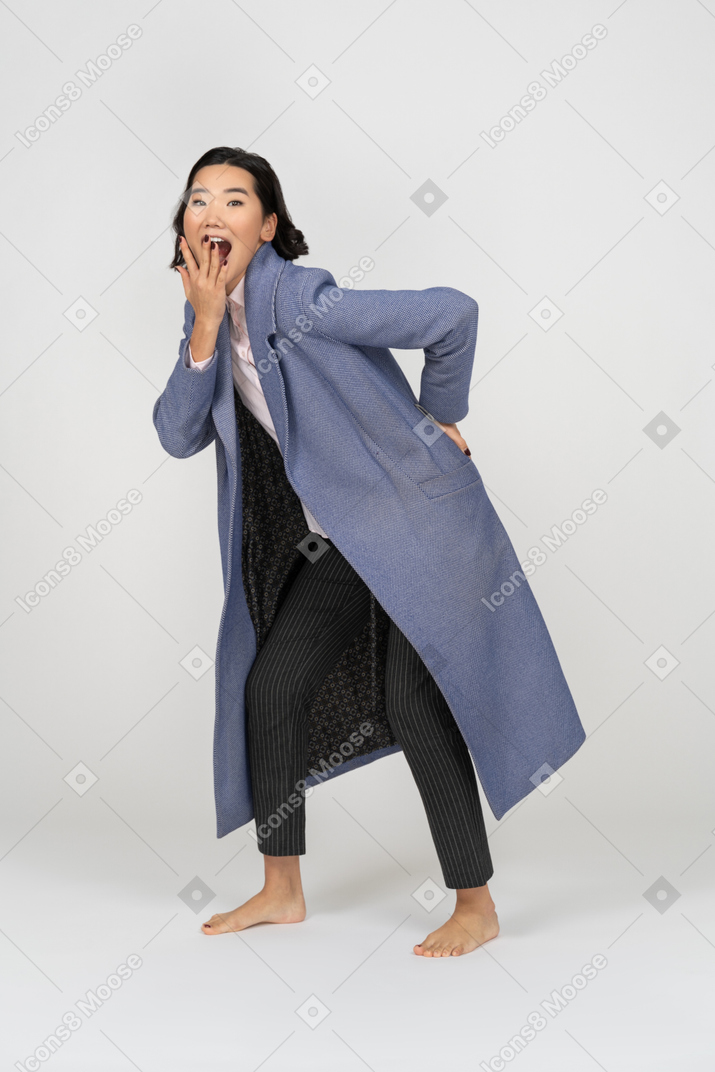 Mujer jadeante con abrigo cubriendo su boca