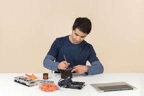 A young man in casual blue clothes working with computer details