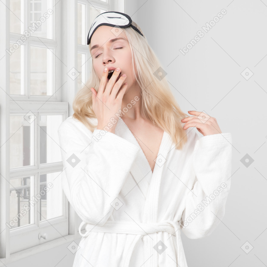 A woman in a bathrobe yawning