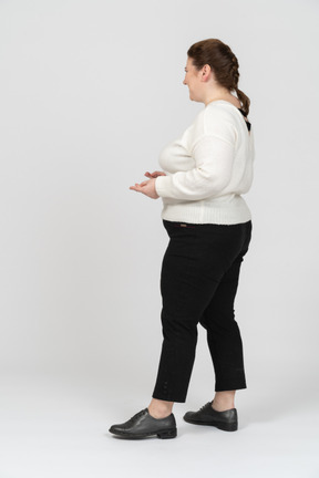 Mujer regordeta en suéter blanco de pie en el perfil