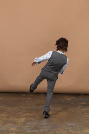 Rear view of a boy in suit kicking something