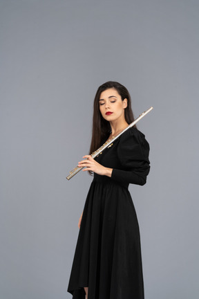 Three-quarter view of a sleepy young lady in black dress holding flute