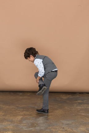 一个穿着西装的男孩单腿站立的侧视图