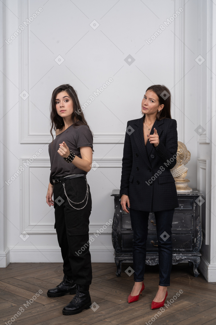 Two serious women pointing at camera