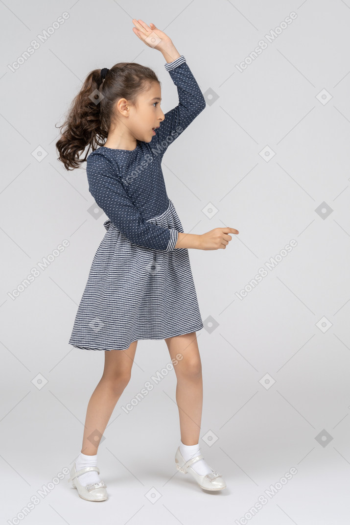 A little girl in a blue dress is dancing