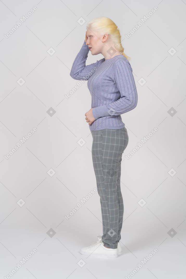 Vista laterale di una donna in abiti casual che tocca il lato della testa