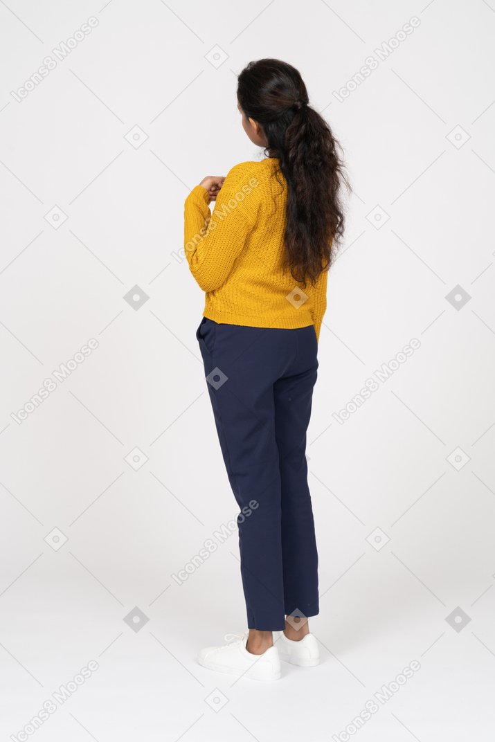 Vista posteriore di una ragazza in abiti casual in piedi con la mano sul petto