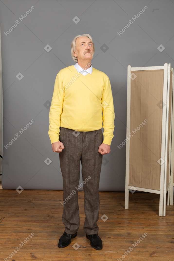 Front view of a strong old man clenching fists while looking up