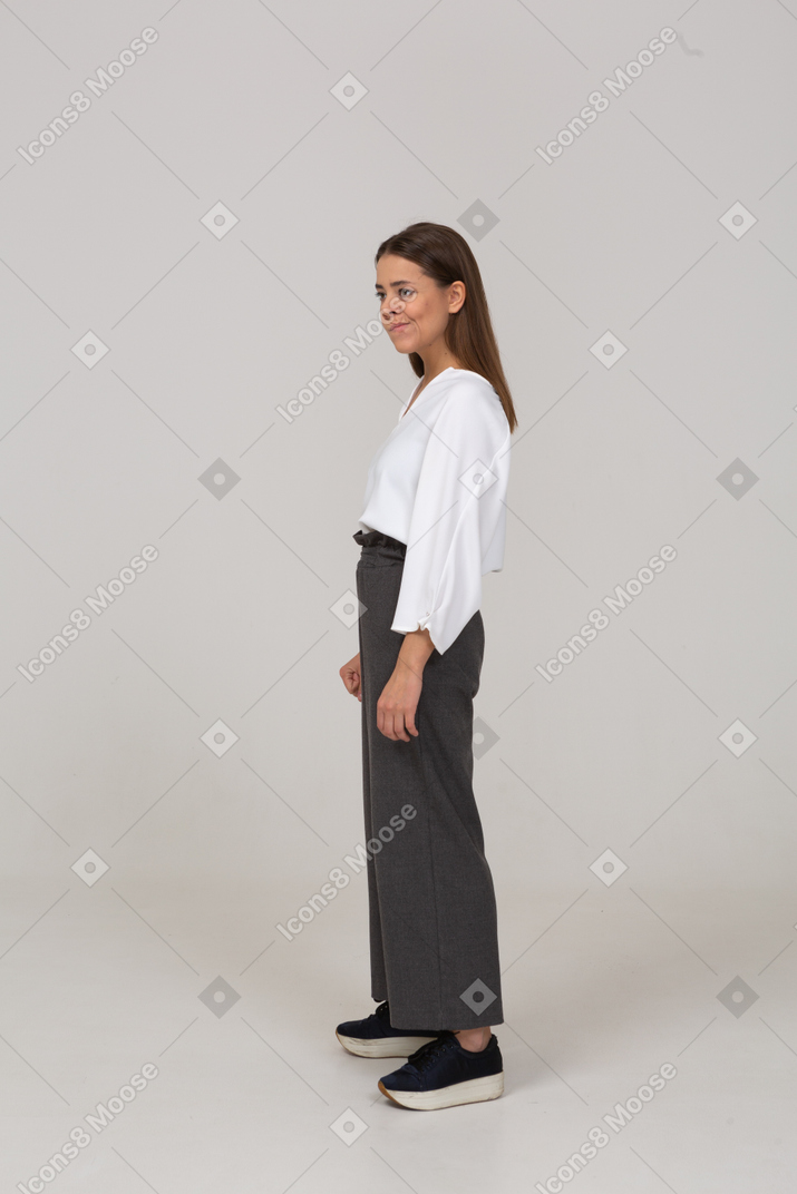 Vista laterale di una giovane donna sorridente in abiti da ufficio