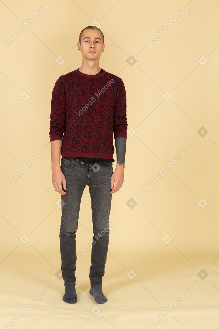 じっと立っている赤いプルオーバーの若い男の正面図
