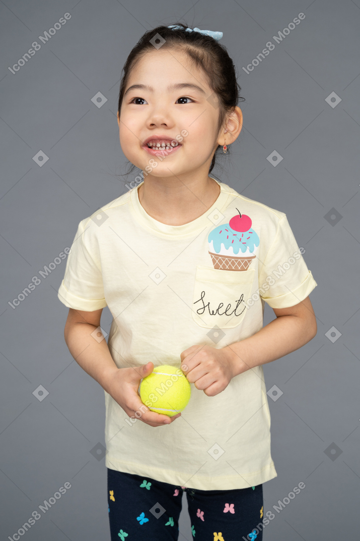 Girl holding a tennis ball and looking away