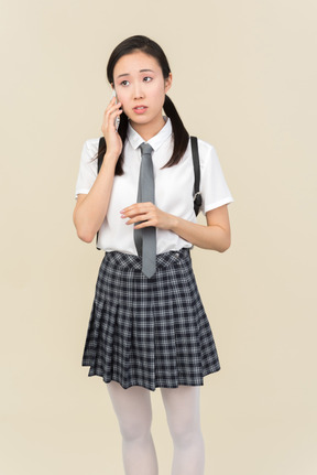 アジアの学校の女の子は電話で言ったことを注意深く聞いて