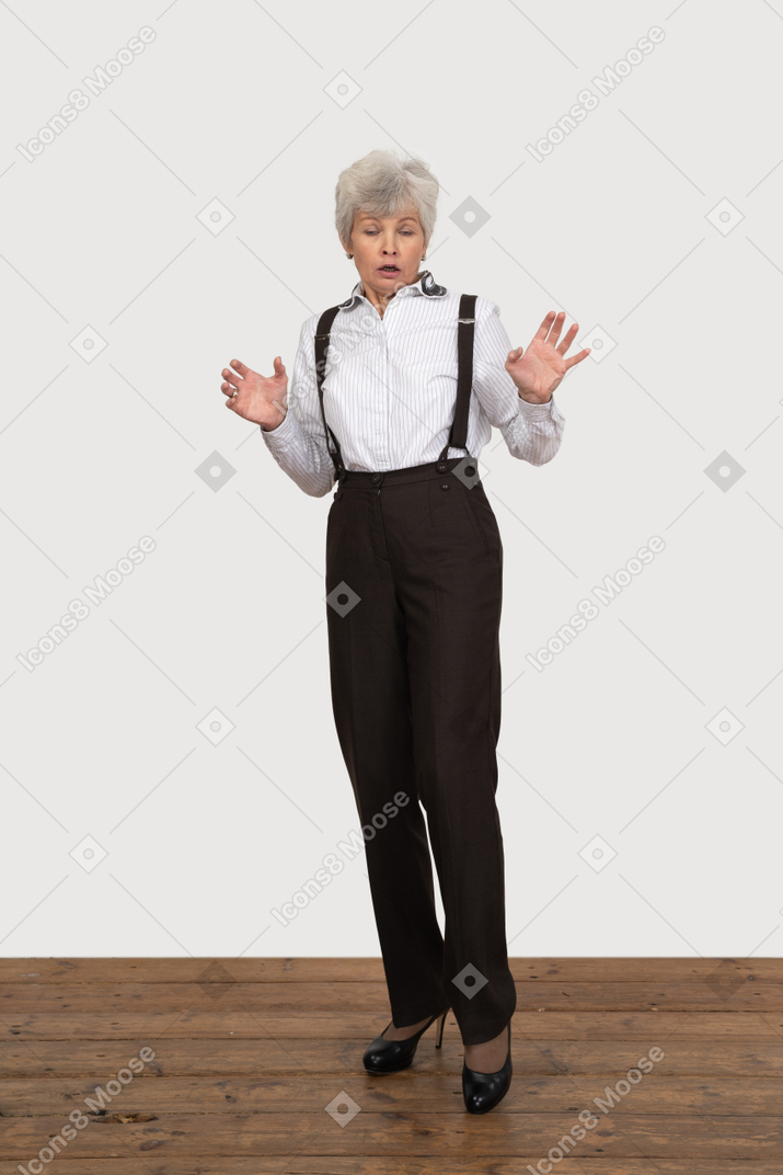Vista frontal de una anciana asombrada levantando y extendiendo las manos