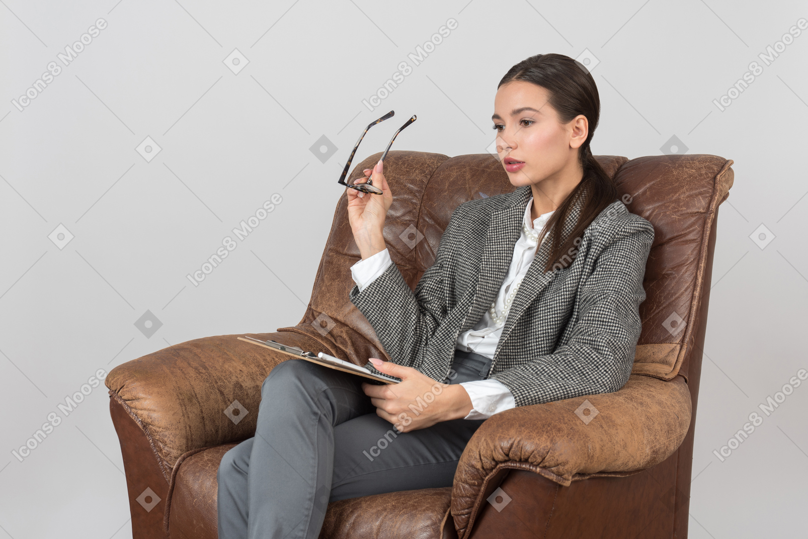 의자에 앉아 안경을 들고 산만 한 젊은 여성 심리학자