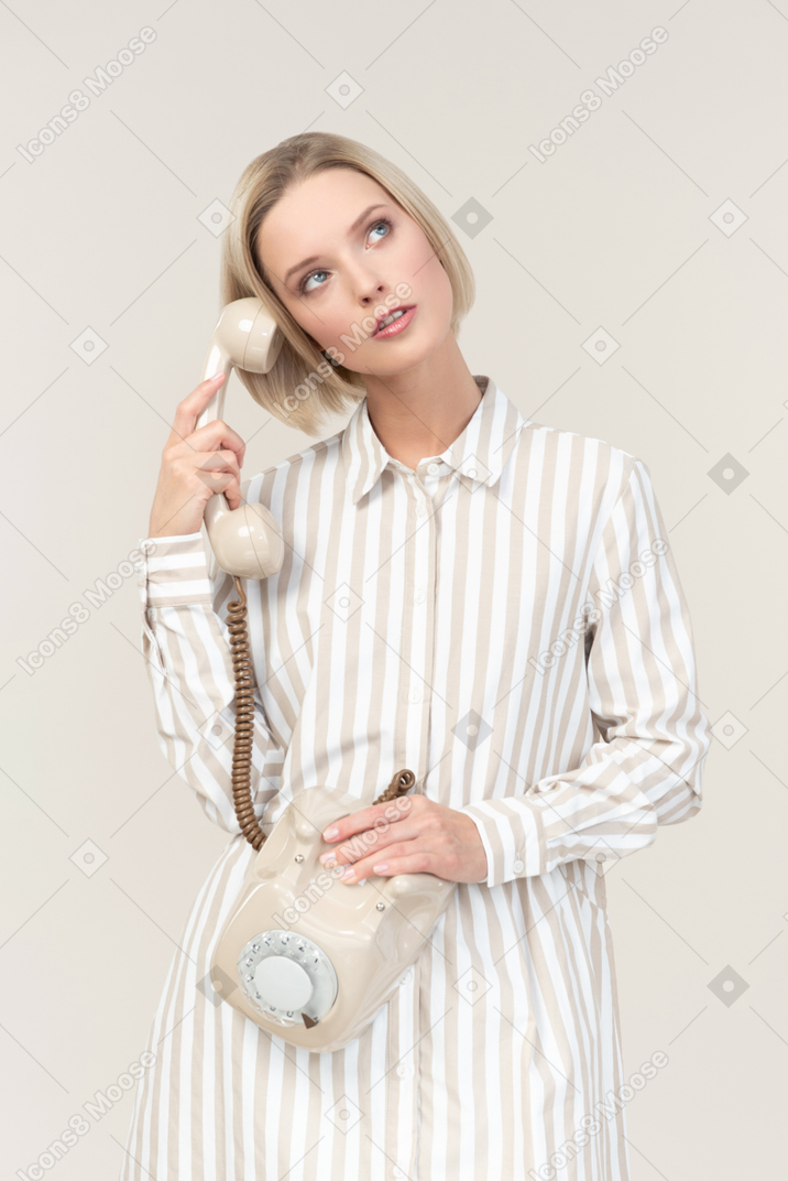 Dreamy young woman holding old rotary phone