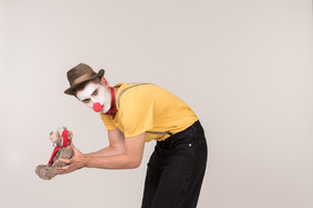 Bend male clown holding teddy bear