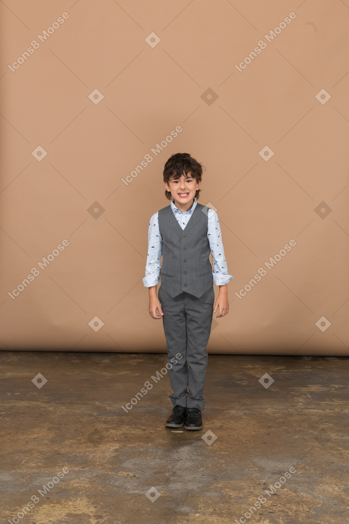 Front view of a cute boy in suite looking at camera and showing teeth