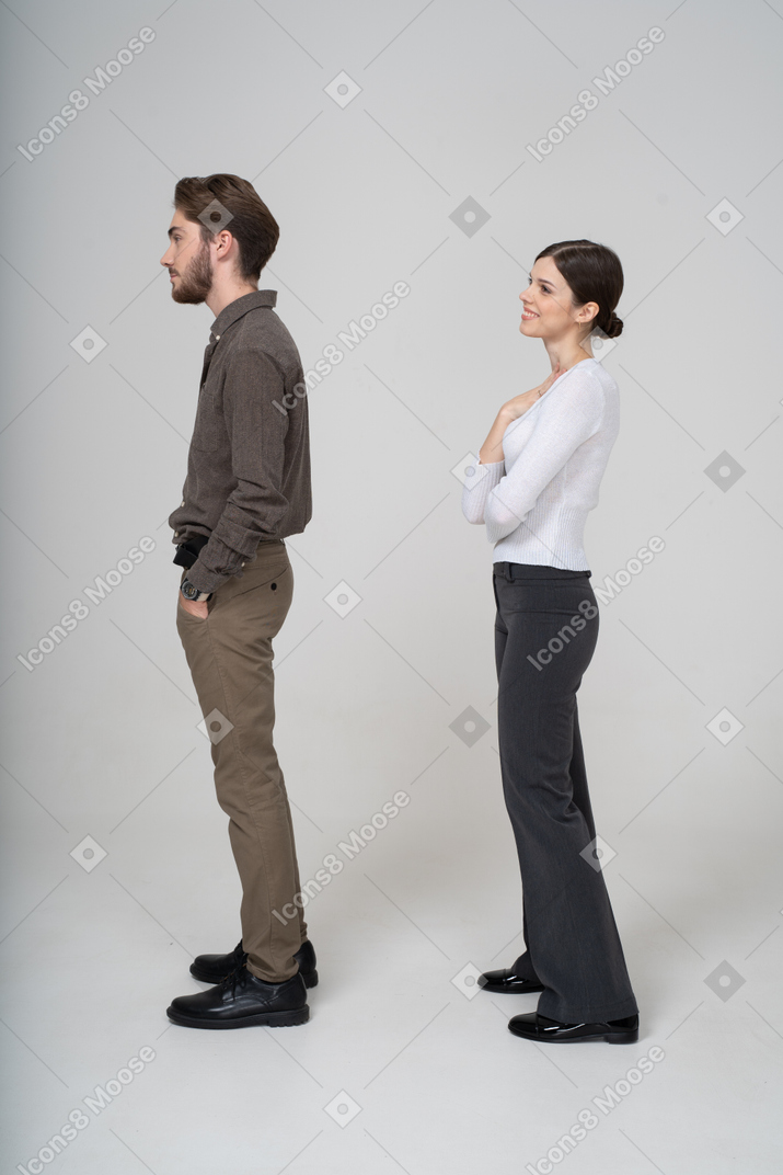 Вид сбоку на мужчину в повседневной одежде, засовывающего руки в карманы, и на довольную молодую женщину
