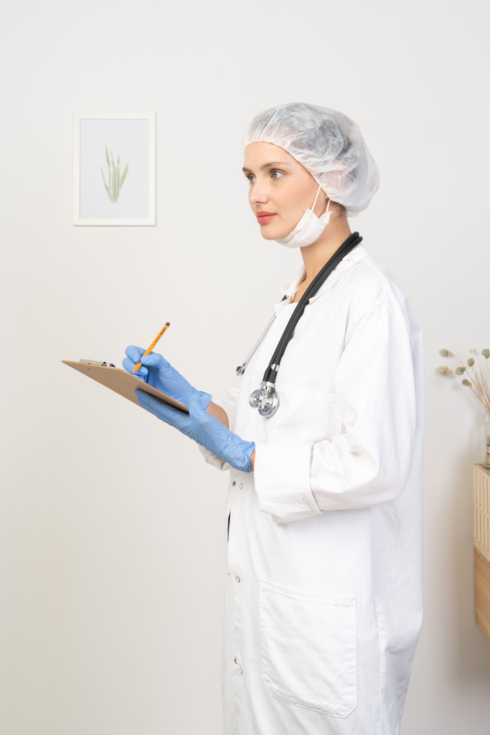 Side view of a young female doctor holding pencil and tablet