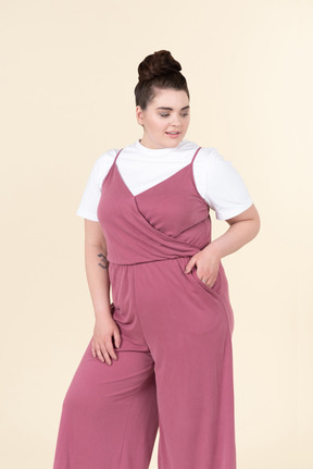 Young plus size woman in a pink jumpsuit, posing against a pastel yellow background