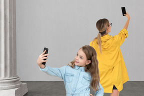A woman and her daughter are taking a selfie in front of a column