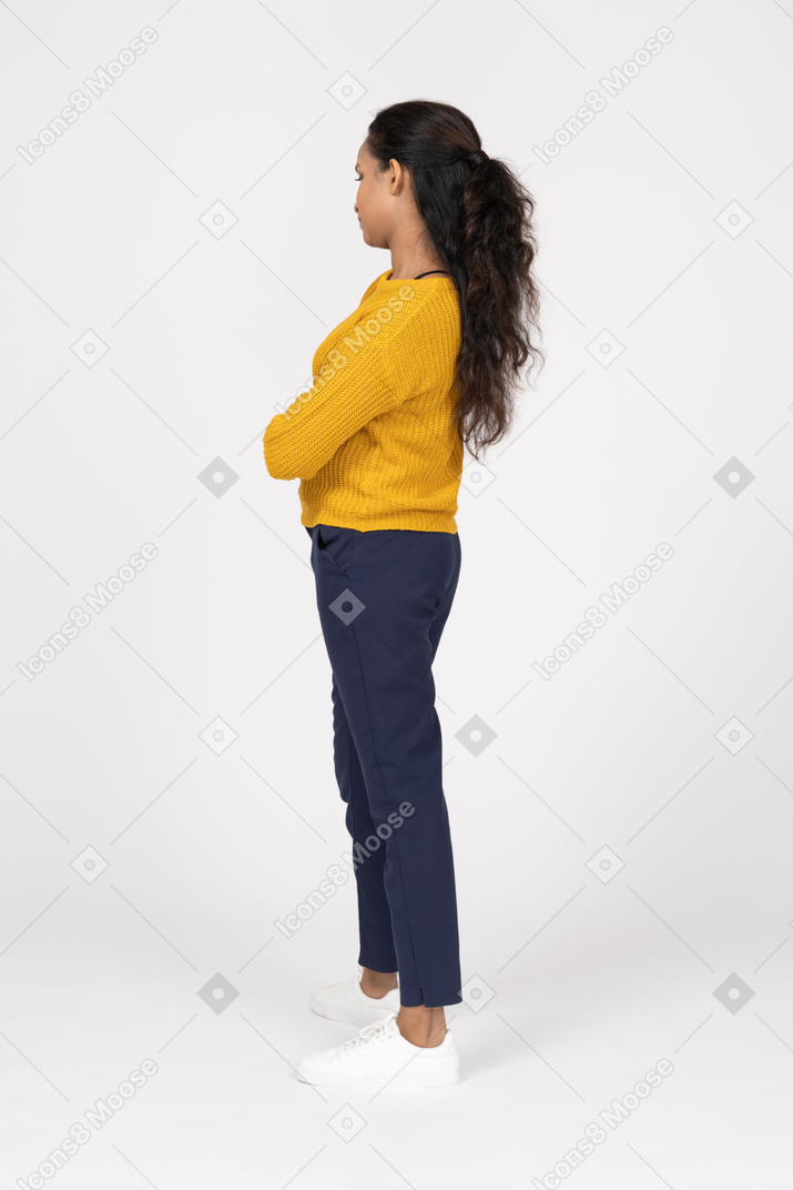 Vista laterale di una ragazza in abiti casual in posa con le braccia incrociate