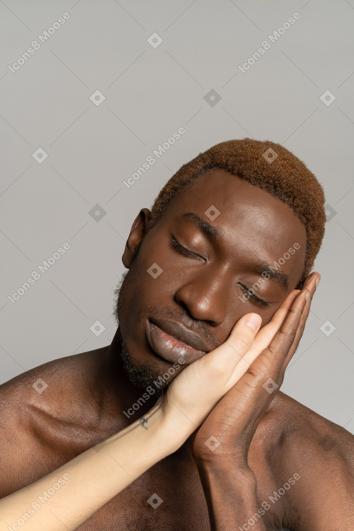 黒人の若い男の顔に触れる白い手