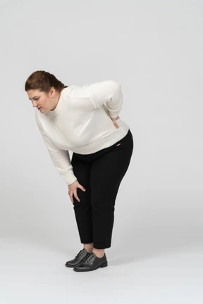 Plus size woman in casual clothes suffering from pain in lower back