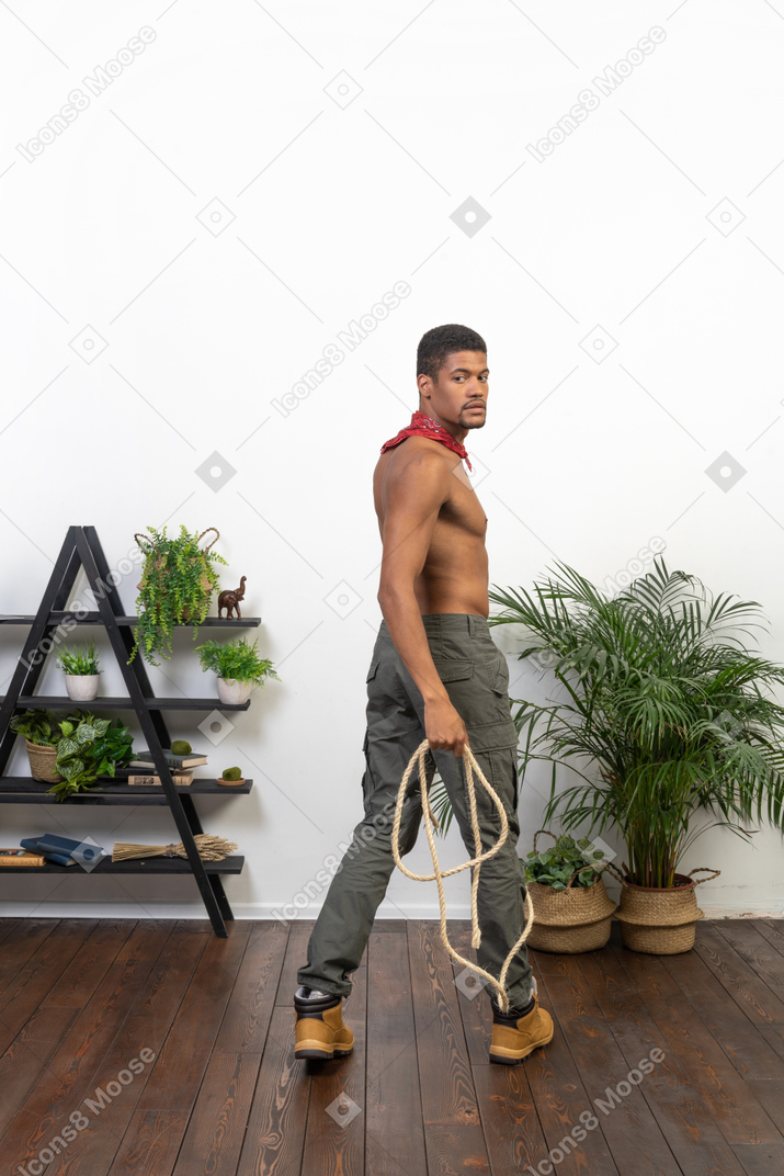Muscular man with a rope in his hand looking back at camera