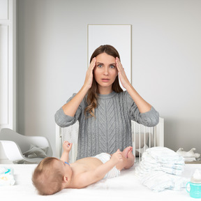 A woman holding her head next to a baby