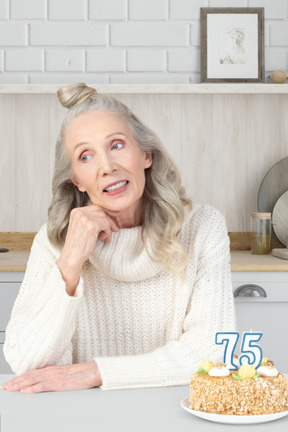 Elderly woman and birthday cake with 75 number candles