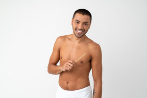 Barechested young man with nice smile holding a toothbrush