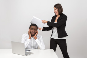 Female boss punching her male employee with bunch of papers